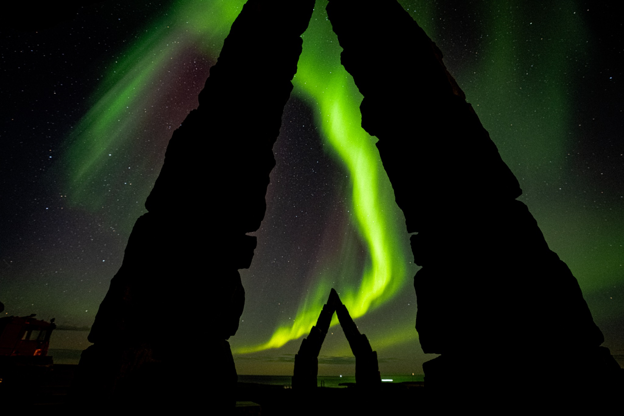 Green northern lights framed by the stone arches of Arctic Henge in Iceland