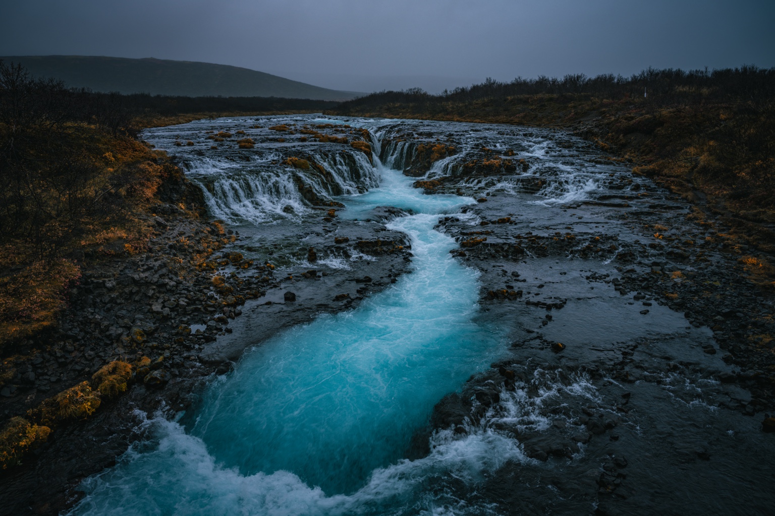 Bright blue water flowing through Brúarfoss waterfall in Iceland