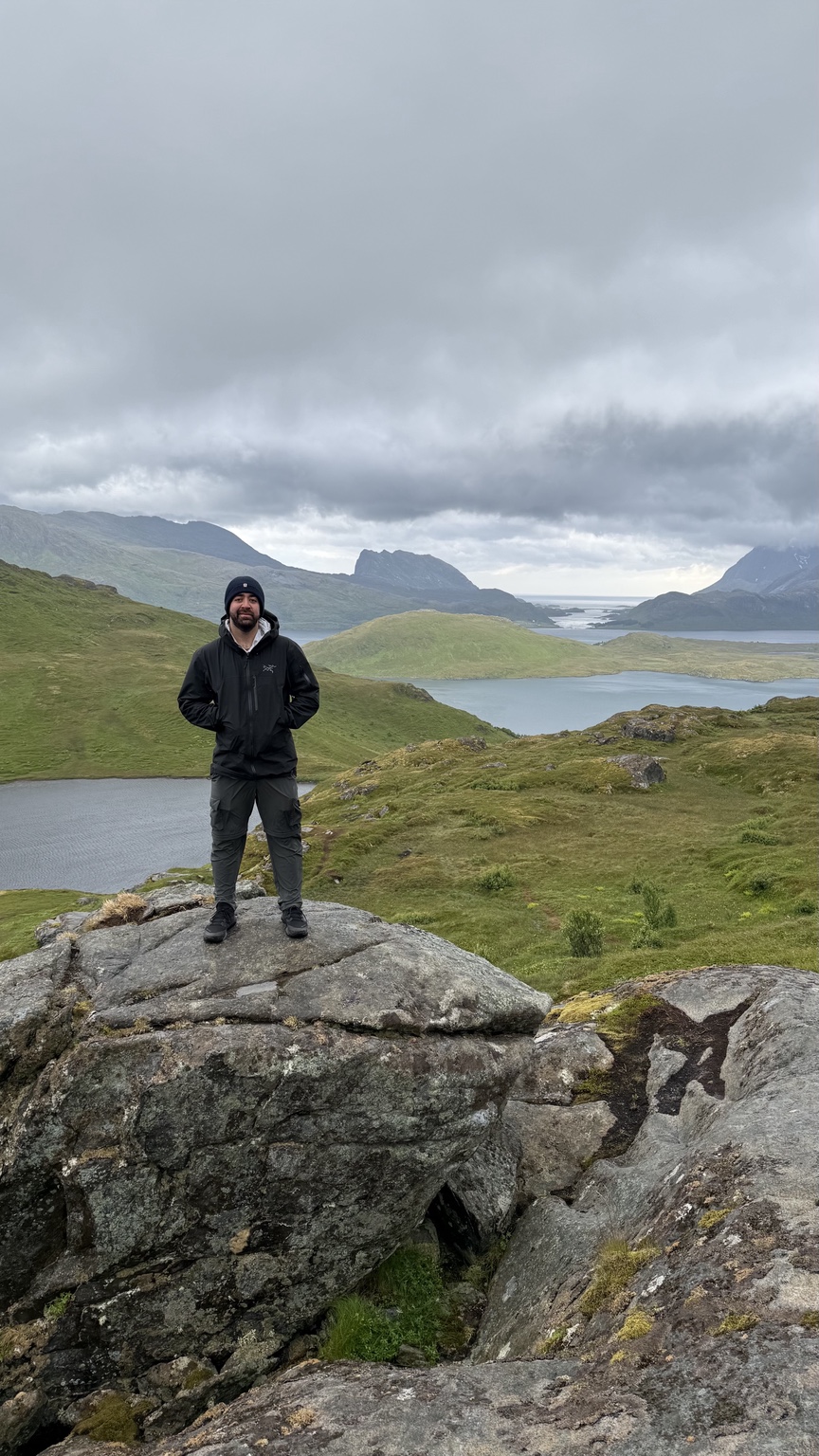 Kia standing on a rocky hillside above mountain lakes in Lofoten